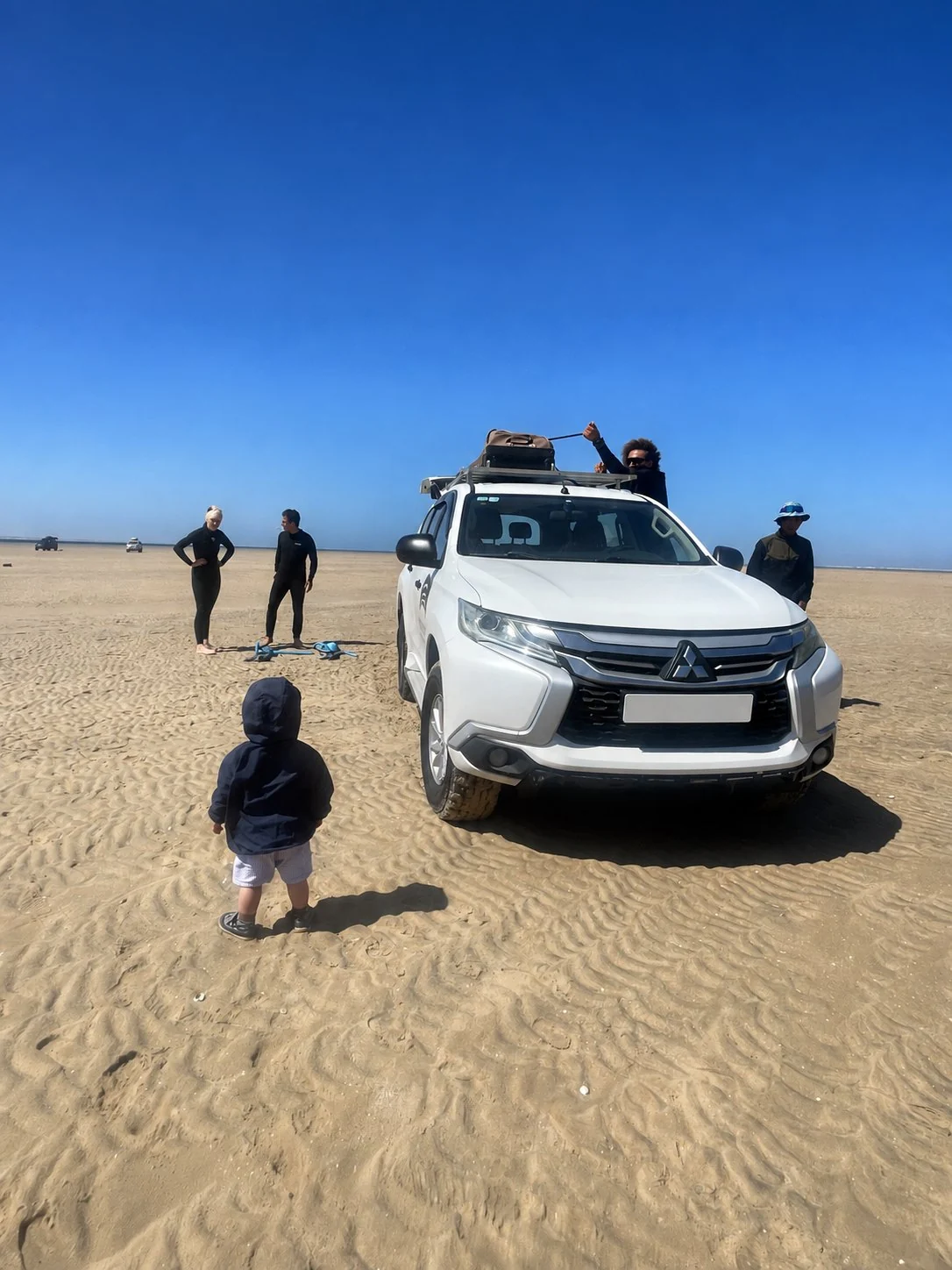 RYDEWIND team preparing kitesurf equipment beside a vehicle in Dakhla
