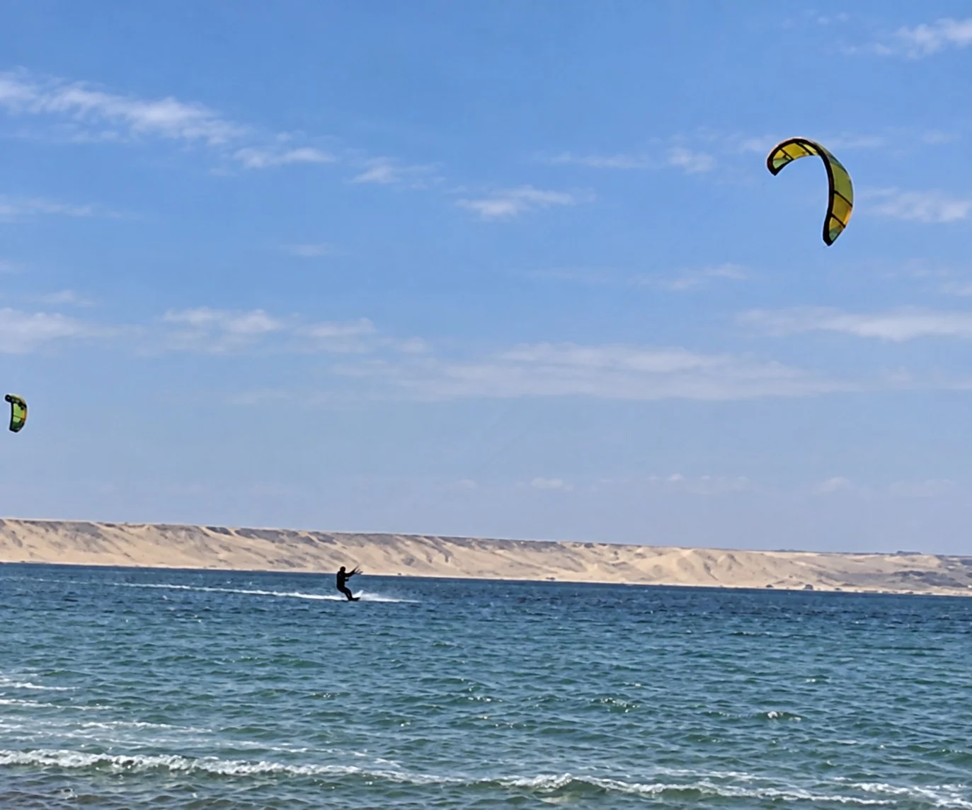 Kitesurfer riding across the lagoon beneath a kite in Dakhla